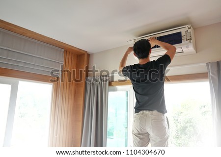 Technician man repairing ,cleaning and maintenance Air conditioner on the wall in bedroom.On site home service,Business ,Industrial concept. Royalty-Free Stock Photo #1104304670
