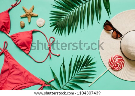 Red, pink bikini suit, lollipop, sunglasses, sea star on plain light cyan background. Empty space for copy, text, lettering. Summer vacation concept.