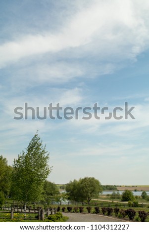 blue sky with white clouds and rural landscape, village house and tree branches