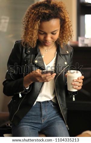 a young African American girl drinks coffee and talks by phone