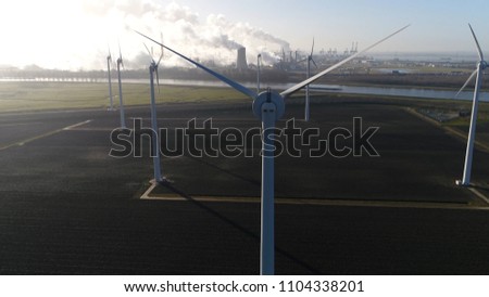 Aerial picture wind turbine park nuclear power plant and industry in background showing the cooling tower rejecting waste heat to the atmosphere forming thick layers of industrial exhaust