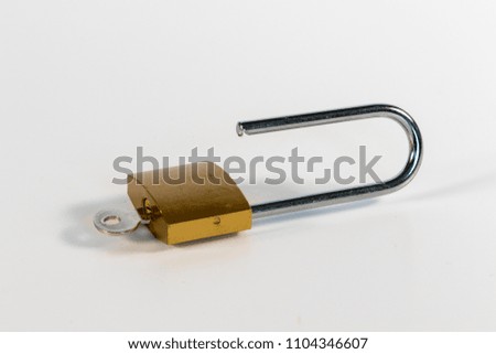 Unlocked golden padlock with a small silver key isolated on white background