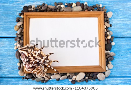 Frame of pebbles and shells on a blue wooden background