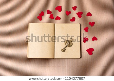 paper hearts around notebook with a decorative retro key