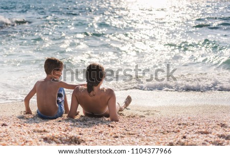 Mother and son making fun on sea sunny beach. Summer vacation holiday concept.
