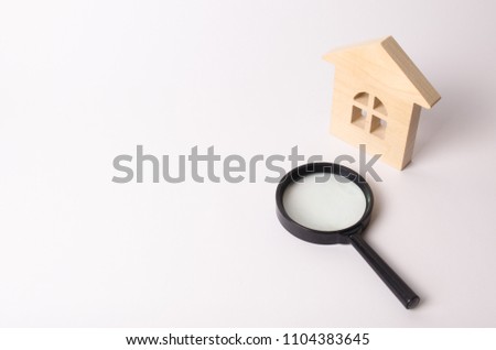 Wooden house and a magnifying glass on a white background. The concept of finding a house, buying or renting an apartment. Realtor services. Search for a new home. Real estate market.