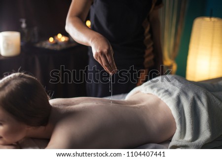 Beautiful young woman relaxing on massage bed while having oil massage at beauty spa. People, beauty and spa, lifestyle and relaxation concept Royalty-Free Stock Photo #1104407441