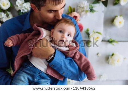 The man tightly hugs his child and kisses him gently in the head. Fatherly tenderness. The girl is studying the room.