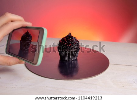 Sweets , food , blogging, closeup of a hand taking picture of black cupcake 