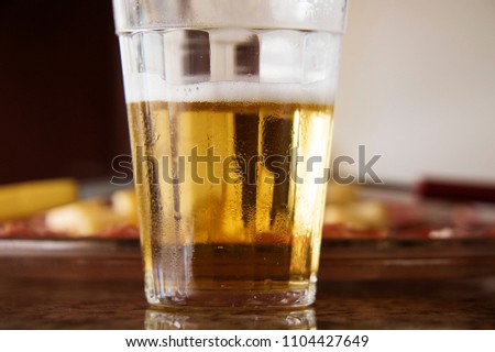 A glass full of beer and foam. Snacks for beer. Snacks of cold cuts salami, lemon and cheeses.Typical Brazilian after-work meal with beer. Selective focus
