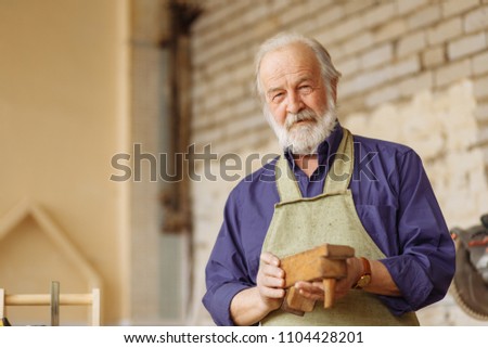 close up portrait of old male doesn't know how to work with wooden plane. look at the camera