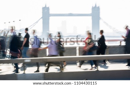 London, UK. Blurred image of office workers crossing the London bridge in early morning on the way to the City of London. Tower bridge at the background