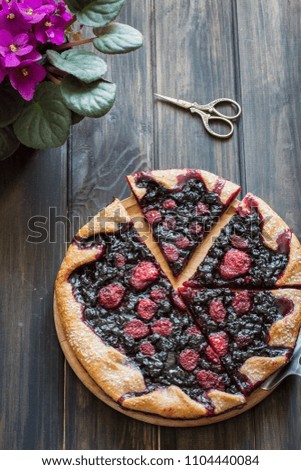 Summer galette with berries, strawberry, blueberry, blackberry and crusty sugar vegetarian dough on  wooden background. Violet flower and vintage scissors. Summer food, summer vegetarian healthy tart
