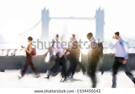 Group of business people walking over London bridge to the City of London. Early morning rush, modern life concept Royalty-Free Stock Photo #1104450542