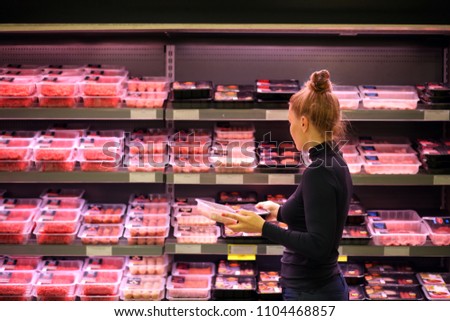 Woman purchasing a packet of meat at the supermarket  Royalty-Free Stock Photo #1104468857