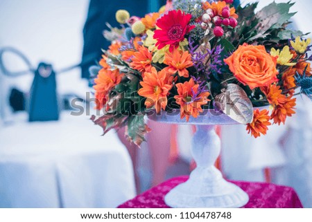 Autumn bouquet of red, yellow and orange flowers, berries and maple leaves on white vintage plate.