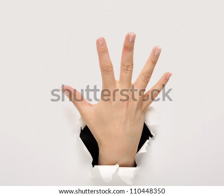 Woman hand making sign through a hole in paper isolated on white background