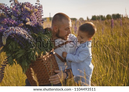 Father hugs his son in the park at the sunset time. People having fun on the field.