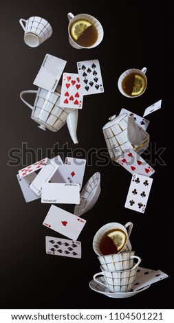 Wonderland background. Mad tea party. Cups, teapot and playing cards falling down the rabbit hole. 