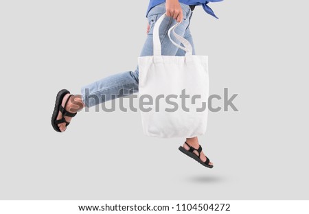 Girl is holding bag canvas fabric for mockup blank template isolated on gray background.  Royalty-Free Stock Photo #1104504272