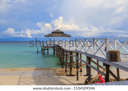 Beautiful scenery landscape view of long wooden jetty and white sand beach with blue sky ocean and green ocean in Mantanani island, North Borneo