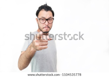 Portrait of young handsome man pointing to you with angry look standing against white background