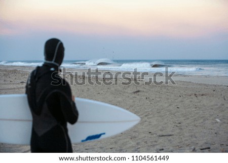 a lone surfer about to paddle out in perfect waves