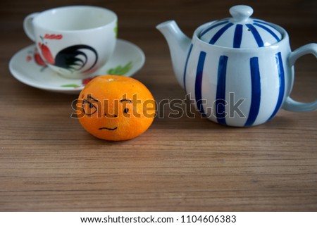 Fresh orange fruit isolated and tea cup,tea pot on wooden background.Emotion face.