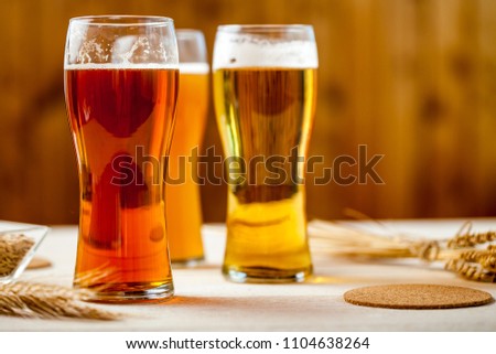 glasses of assorted beer with wheat on a wooden table background for tasting
