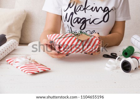 Closeup of girl's hands wrapping Christmas of birthday gifts and decorating then with ribbons and tags. Holiday season
