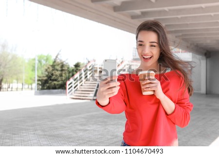 Attractive young woman taking selfie with phone outdoors