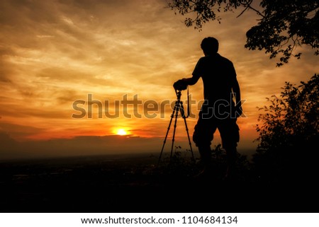 Silhouette photographer with sunset background
