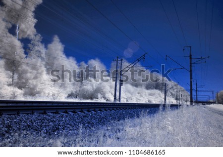 Surreal railway tracks. Translucent trail of the train. Infrared photography. Train line in infrared mode