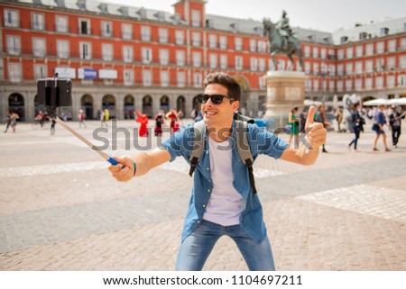 Attractive young caucasian tourist student man having fun happy and excited taking a selfie with smart phone in Plaza Mayor, Madrid, Spain. Travel,vacation, holidays in European city concept.