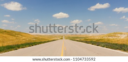 Horizontal Photo of an Ultra Wide North Dakota Highway with yellow lines, blue sky and clouds Royalty-Free Stock Photo #1104733592