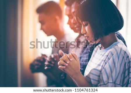 Asian Christian groups sitting within the Church Catholic. They clasped hands and closed his eyes and prayed for blessings from God. A pale sun shone in a place of worship with copy space. Royalty-Free Stock Photo #1104761324