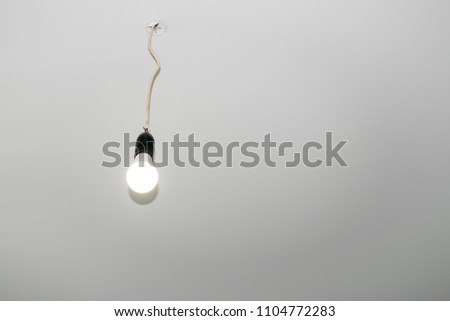 The electric bulb on the wire hangs from the suspended ceiling.