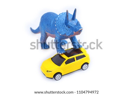 Toy triceratops dinosaur attack yellow car isolated on white background
