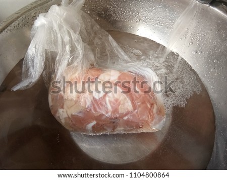 How to Defrost a frozen chicken into water.  Royalty-Free Stock Photo #1104800864