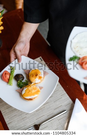 Concept picture, staff is holding a egg benedict for breakfast