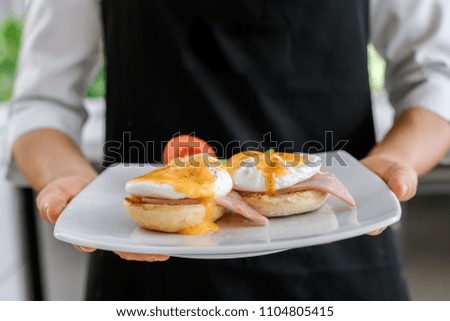 Concept picture, chef is holding a egg benedict for breakfast