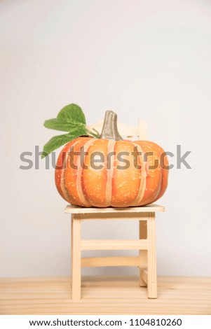 Artificial Pumpkin Placed on Wooden Chair, White Backdrop