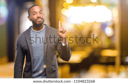 African american man with beard raising finger, the number one at night