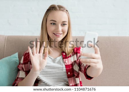 close-up portrait of teen student girl making video call with smartphone and waving at camera
