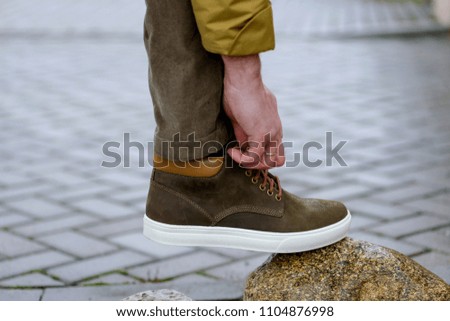 Men corrects shoelaces. Fashion street stylish boots
