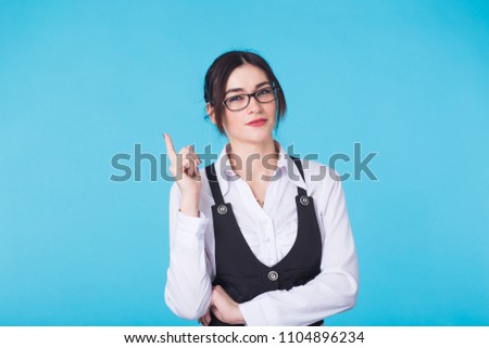 Young pretty girl holding finger up having idea and posing on blue background.