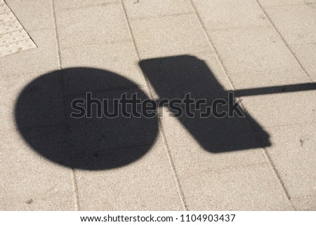 A stop sign shadow on a pavement