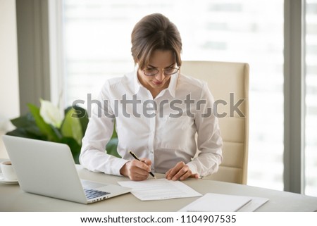 Serious successful businesswoman puts signature on business contract, millennial female entrepreneur signing paper doing paperwork at workplace, woman boss working with documents in office Royalty-Free Stock Photo #1104907535