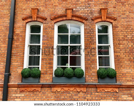 Three windows in a red brick wall Royalty-Free Stock Photo #1104923333