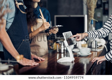 customer self service order drink menu with tablet screen at cafe counter bar,seller coffee shop accept payment by mobile.digital lifestyle concept.Blank space for display of design Royalty-Free Stock Photo #1104959774